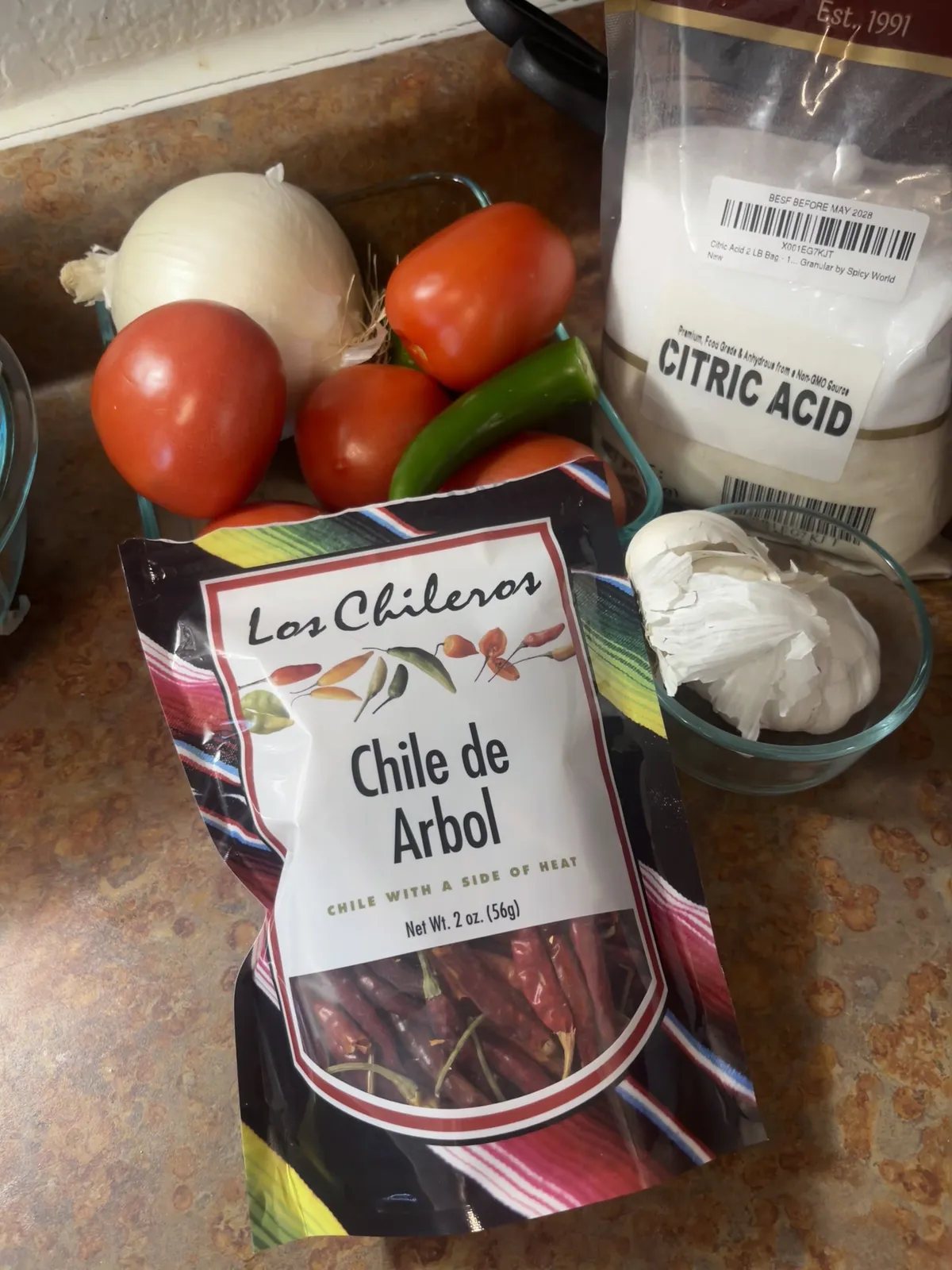 Chile de arbol, tomatoes, limes, onion, garlic, and citric acid on the counter